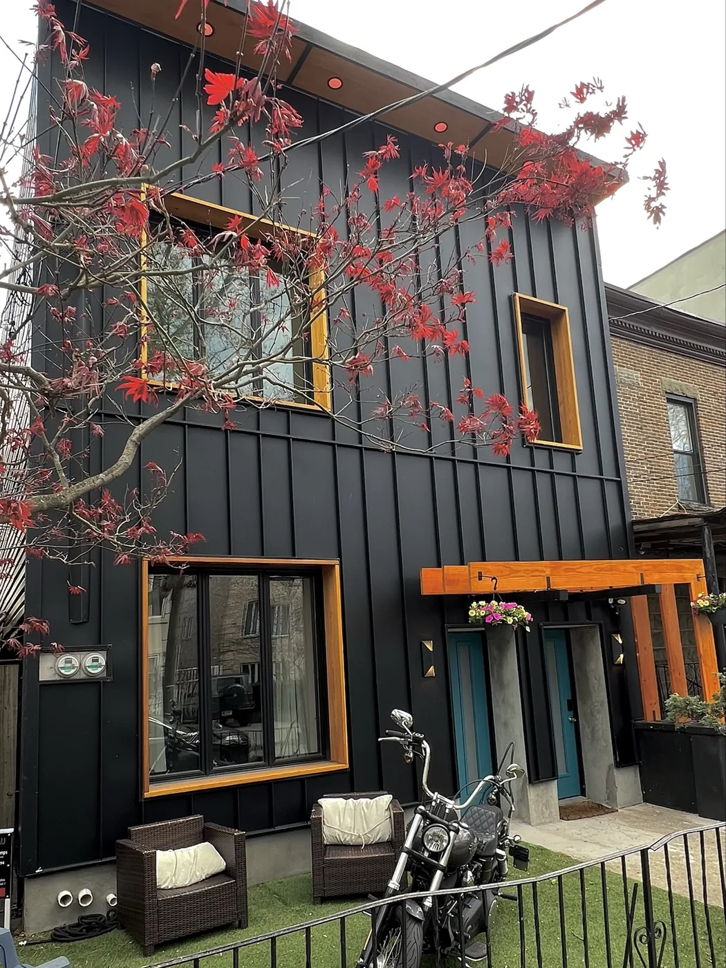 1818 25th Road Astoria after renovation — three-story black board-and-batten facade with cedar-framed windows