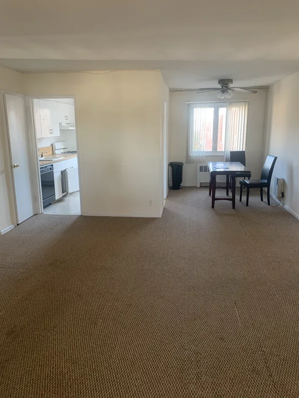 The original Bayside kitchen layout before remodeling, a separate closed-off galley kitchen reached through a narrow doorway from the carpeted dining area