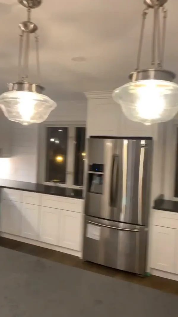 Brass pendant lights over the island against the shiplap window wall