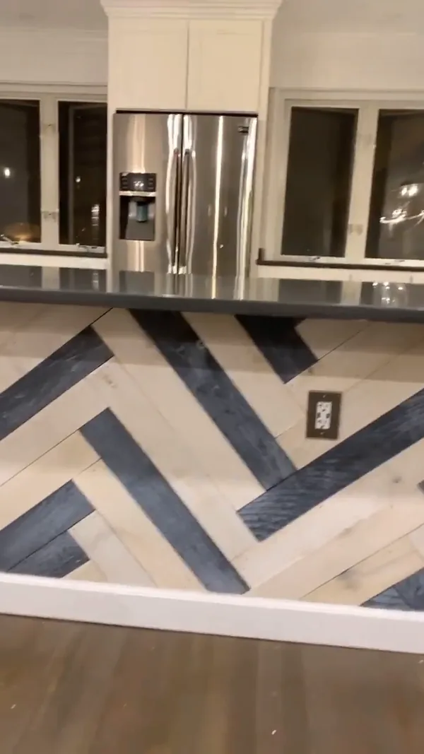 The slide-in range with herringbone tile backsplash and white shaker cabinets in the finished Bayside kitchen