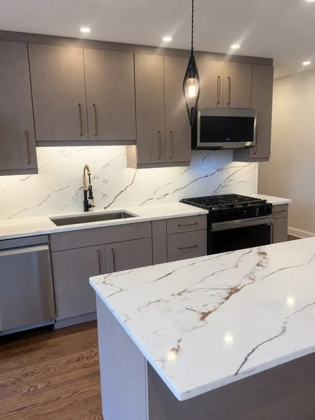 The finished Bayside kitchen looking across the waterfall quartz island toward the range and full-height backsplash