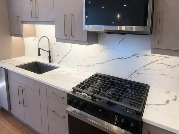 Undermount sink, gooseneck faucet and quartz counters with the matching full-height backsplash behind the range