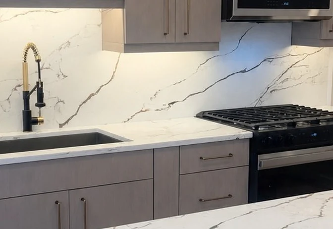 The same wall finished with soft grey cabinetry, an undermount sink, quartz counters and a matching full-height quartz backsplash