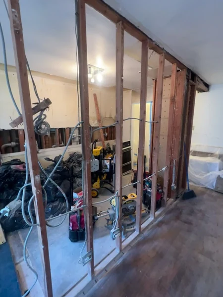 Demolition underway in the Bayside apartment with the dividing wall stripped to studs and floor protection in place
