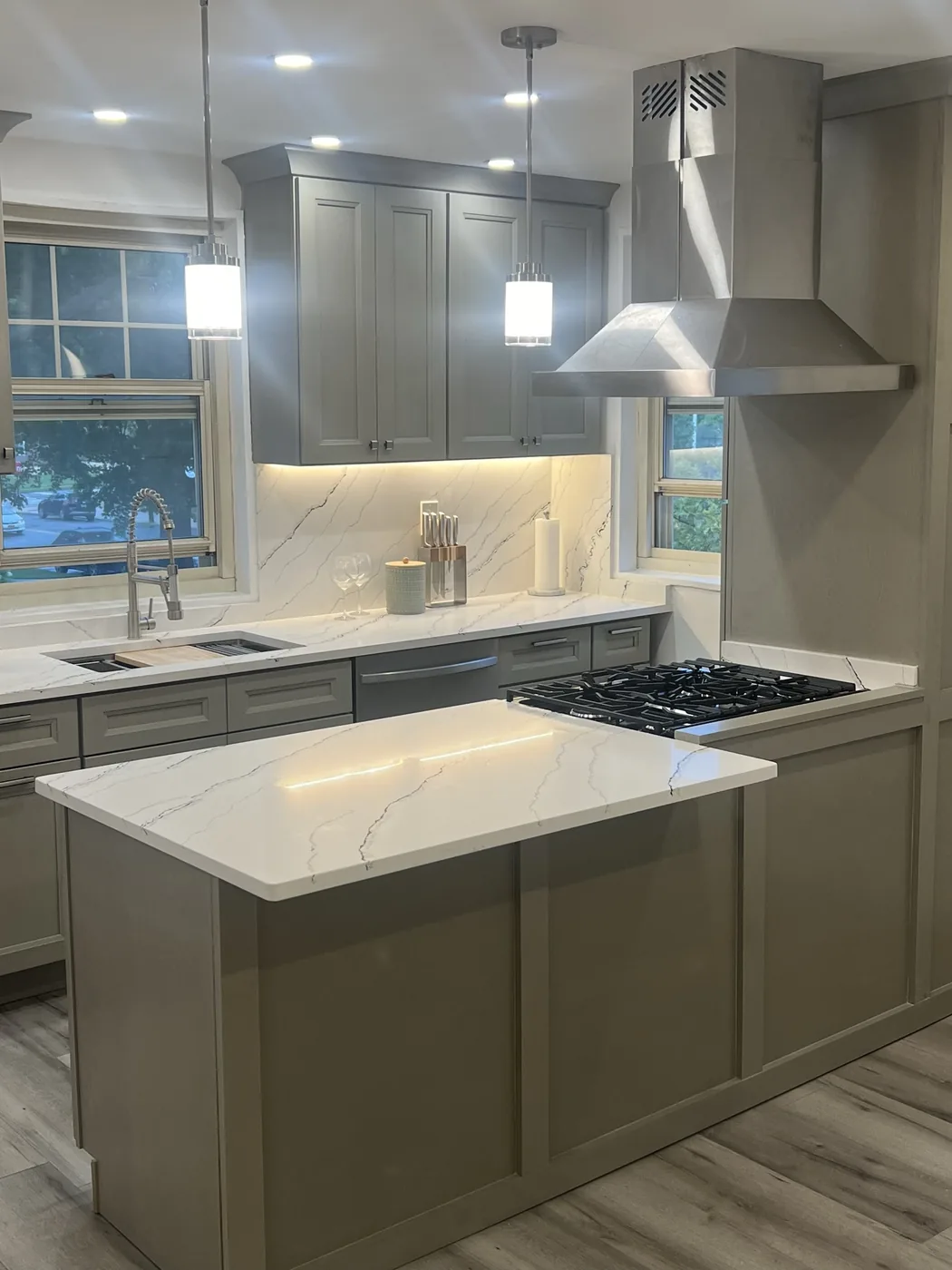 Douglaston kitchen after renovation, grey shaker cabinets, veined quartz counters and stainless chimney hood