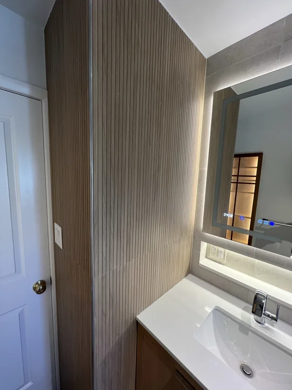 Floor-to-ceiling fluted wood paneling wrapping the corner beside the bathroom entry door
