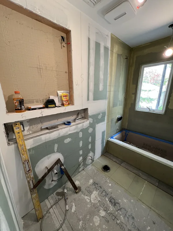 The Great Neck bathroom at rough-in, with greenboard, taped seams and the recessed cabinet opening framed into the vanity wall