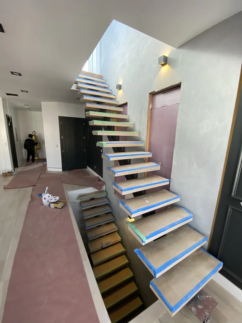 White oak treads masked with protective tape during the staircase build.