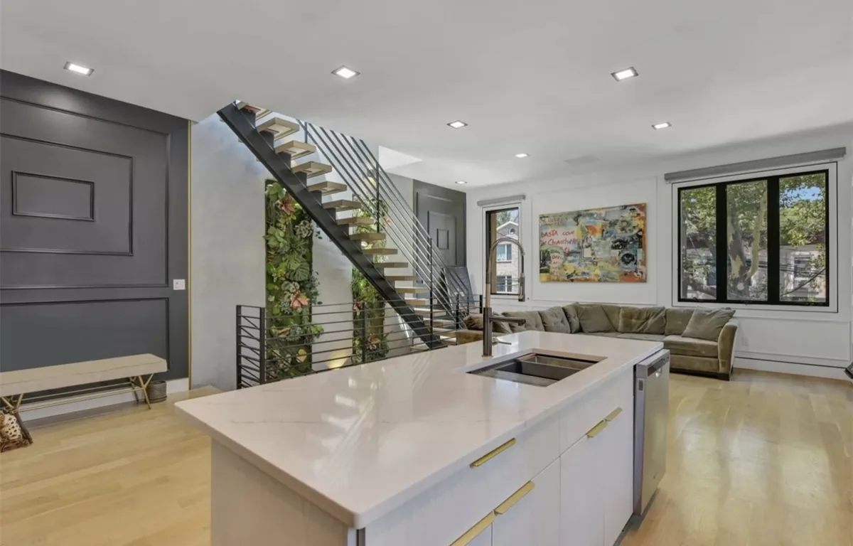 The finished floating staircase framed by the kitchen island and living area.