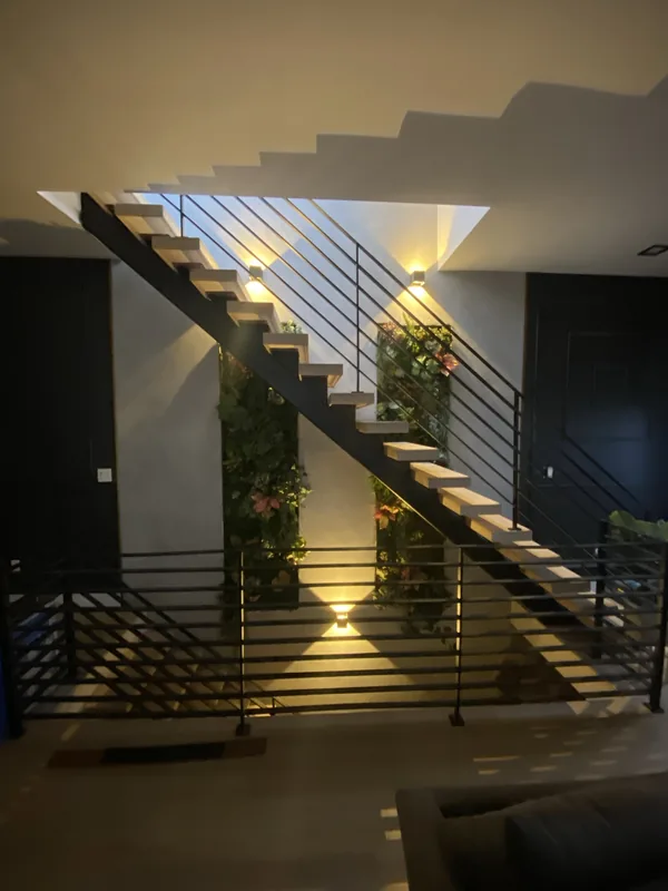 The floating staircase at night, lit by sconces and accent lighting.