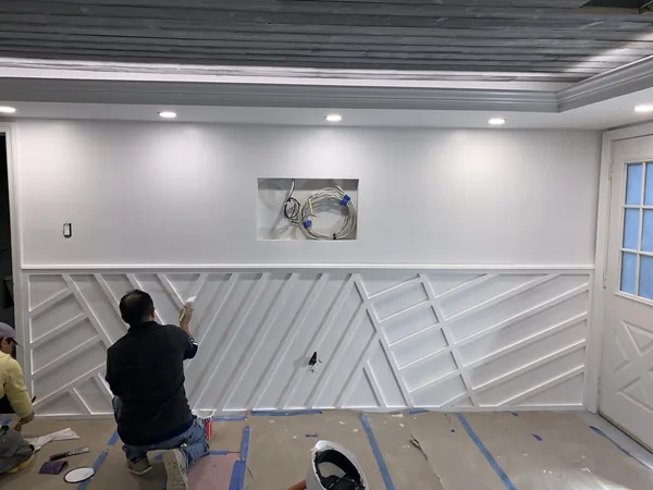 A carpenter installing the custom white geometric millwork on site.