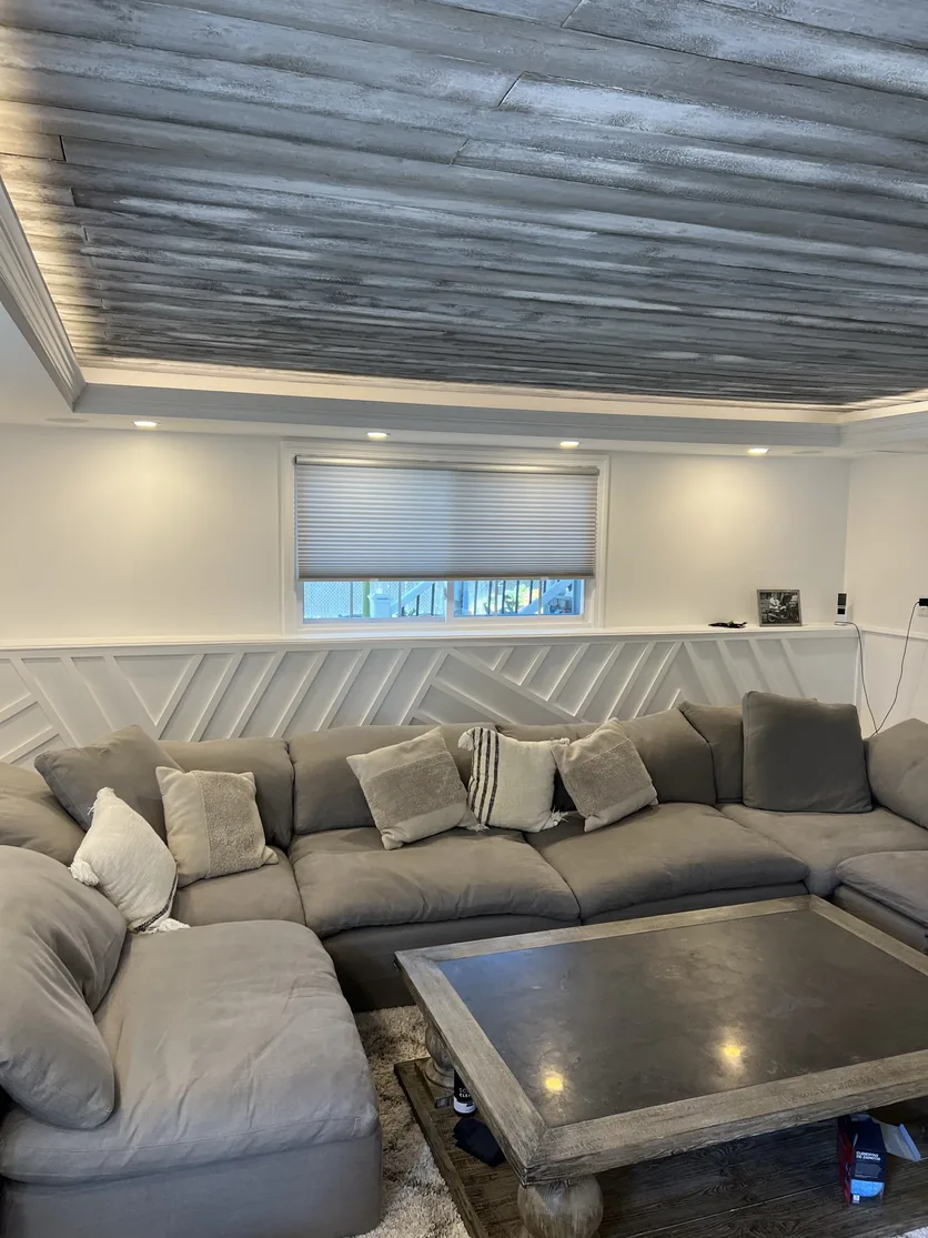 Close view of the white geometric slat millwork below the window, with the wood tray ceiling above.