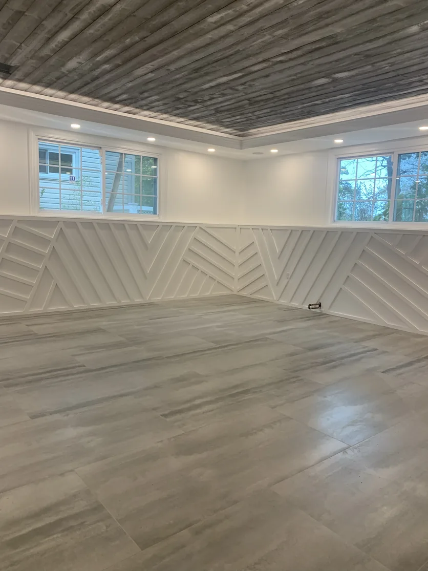 The finished, unfurnished family room showing the large-format porcelain floor and white millwork.