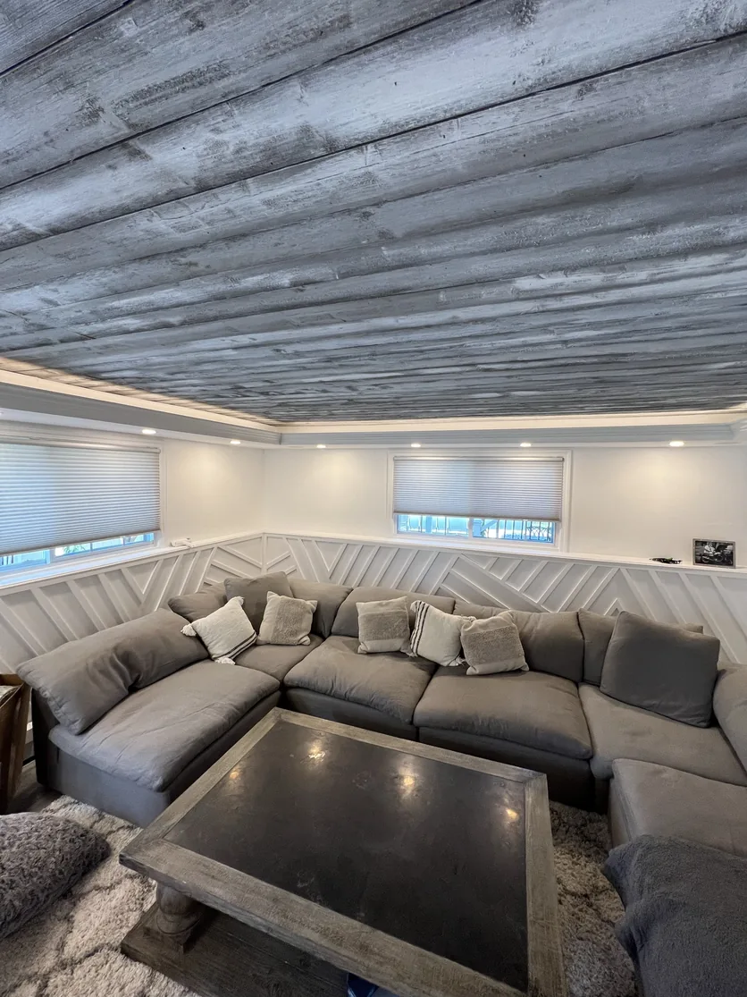 High-angle view of the seating area with the wrap-around white millwork and the complete wood-clad tray ceiling.