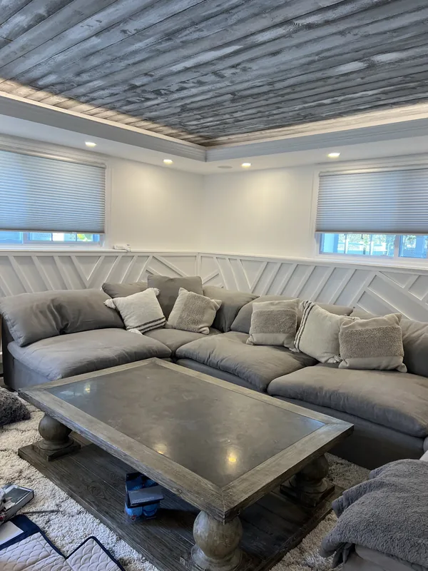 Wide view of the furnished family room with sectional, millwork and tray ceiling.