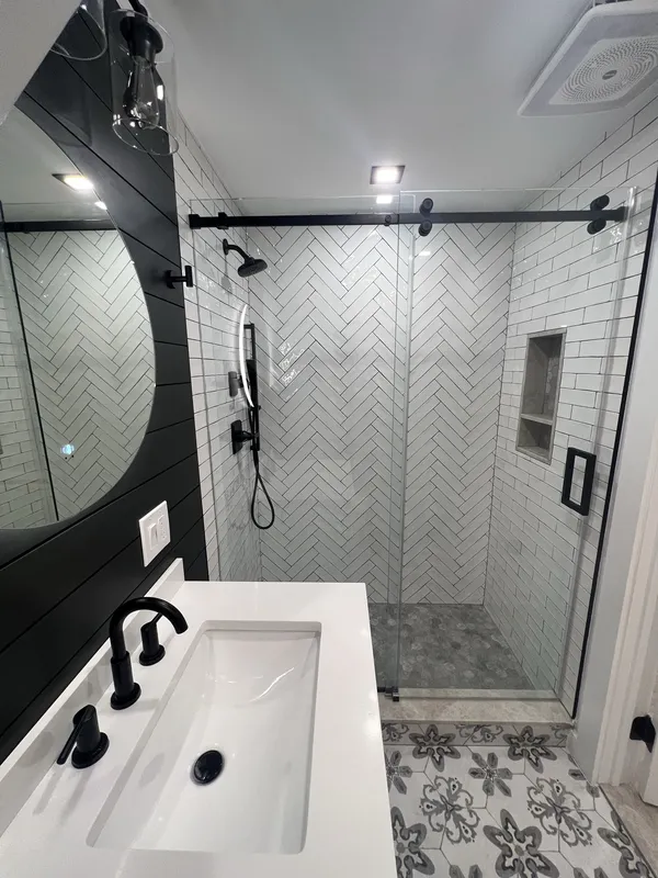 Wide view of the finished bathroom, shower on the left, vanity and mirror on the right.