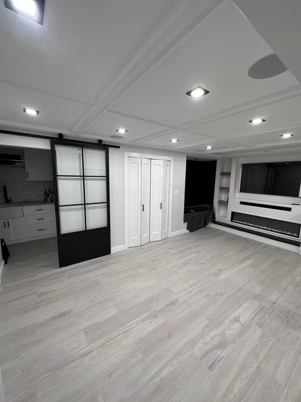 The finished basement: coffered ceiling, glass slider, media wall with fireplace.
