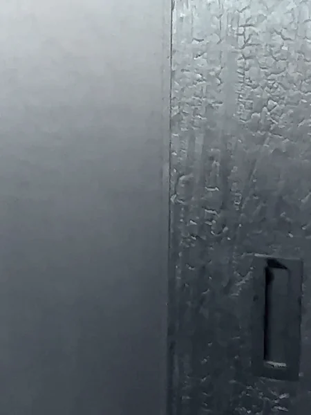 Recessed flush pull let into the charred cedar face of an oversized closet door, beside a stile with heavy alligator-skin crackle