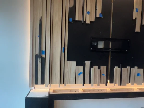 Cantilevered console frame open before cladding, beneath the slat wall in progress