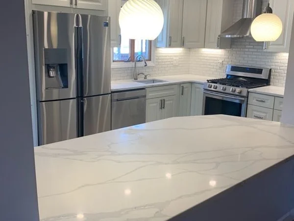 After: finished Whitestone kitchen with glass globe pendants over the quartz peninsula