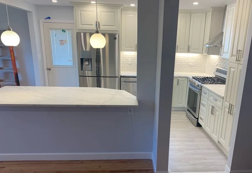 After: the same view with a widened opening, quartz peninsula, white cabinetry and refinished hardwood floor