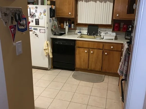 Before: sink wall of the original kitchen with laminate countertop and black dishwasher